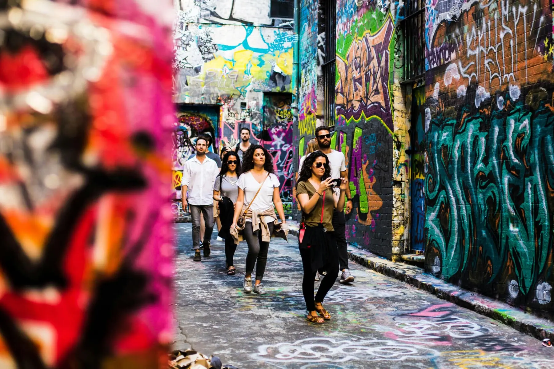 People walking through a graffiti covered laneway in Melbourne